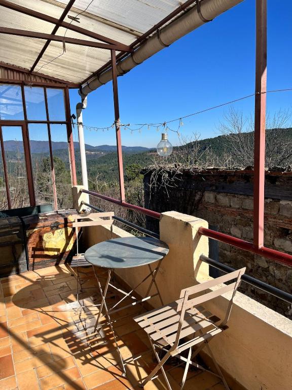 une table et des chaises sur un porche avec vue dans l'établissement Joli logement proche du Mont Lozère, à La Vernarède