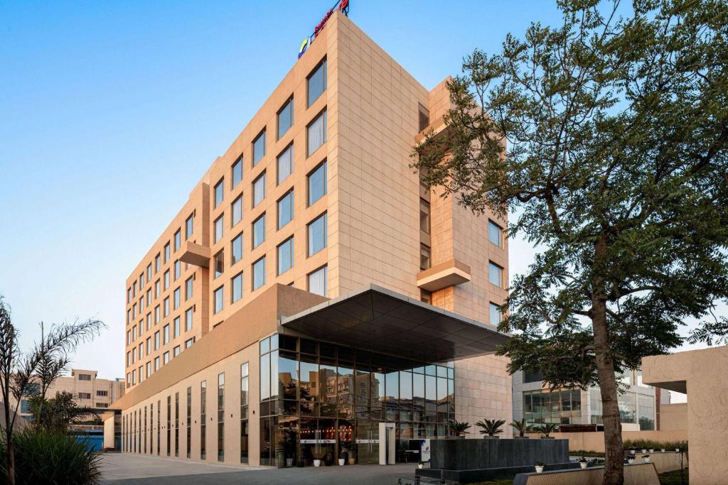 a building with a flag on top of it at Ramada Encore By Wyndham Bhiwadi Phool Bagh Chowk in Bhiwadi