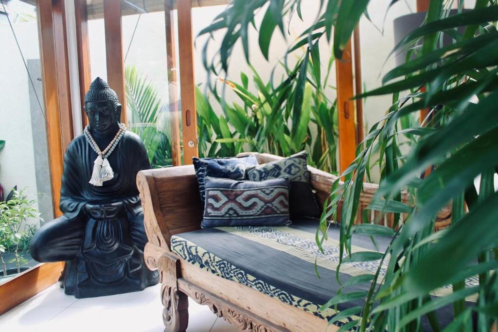 a statue sitting next to a bench with pillows at Dwipa Peaceful, spacious 2 bedroom villa in Sanur