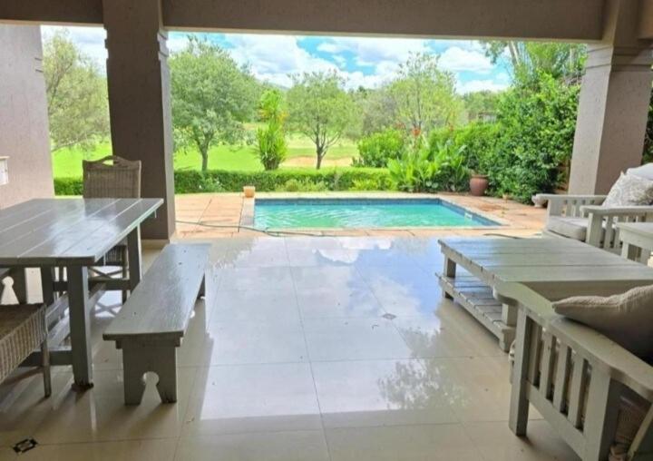 a patio with a table and a swimming pool at Pecanwood Estate Dream views 4 bedroom Villa with pool in Hartbeespoort