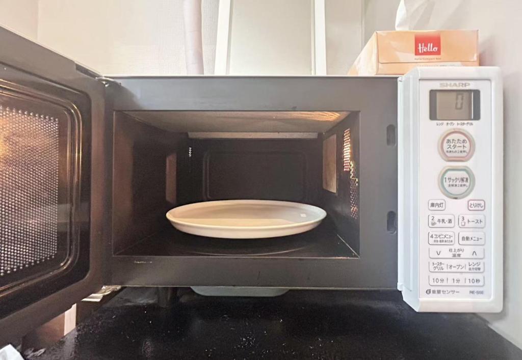 un micro-ondes avec une assiette à l'intérieur dans l'établissement Ueno Sakura House, à Tokyo