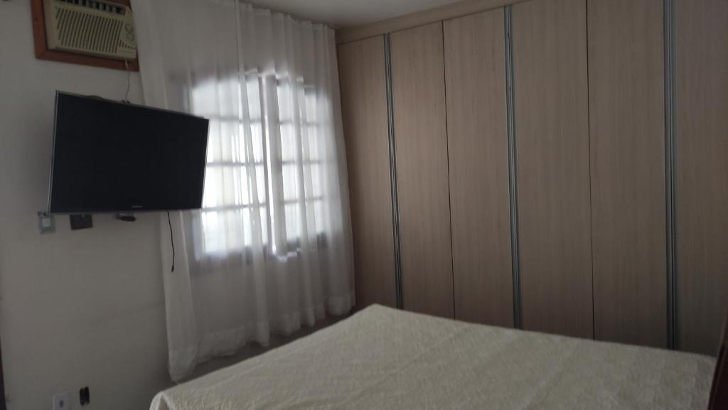 a bedroom with a bed and a flat screen tv at Hostel Leandros Eldorado in Contagem
