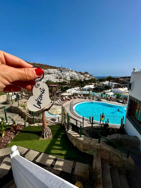a hand holding a house key with a view of a pool at Sunny Monaco Puerto Rico in Mogán