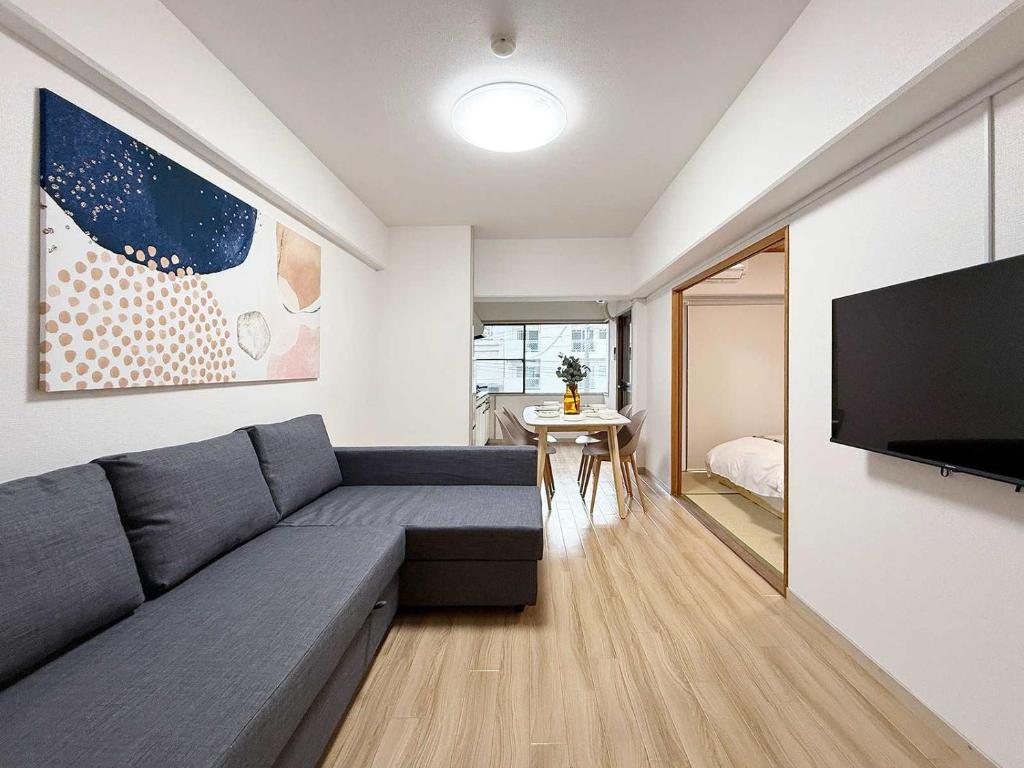 Una sala de estar con un sofá y un televisor de pantalla plana. en Residence Yu by b hotel - Relaxing 2BR Near City Center Dining & Kitchen, en Hiroshima