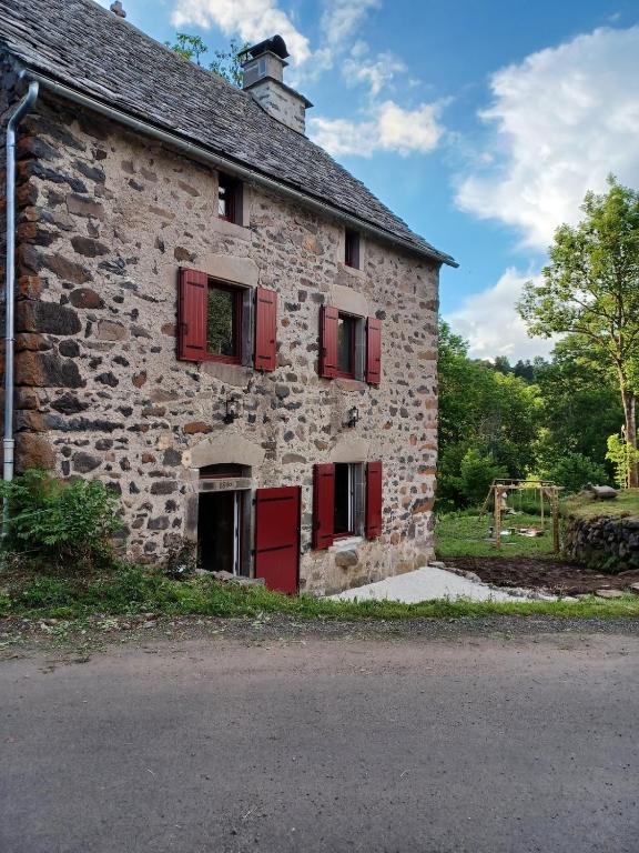 - un vieux bâtiment en pierre avec des fenêtres à volets rouges dans l'établissement Lou Cantou des randonneurs, à Neussargues en Pinatelle
