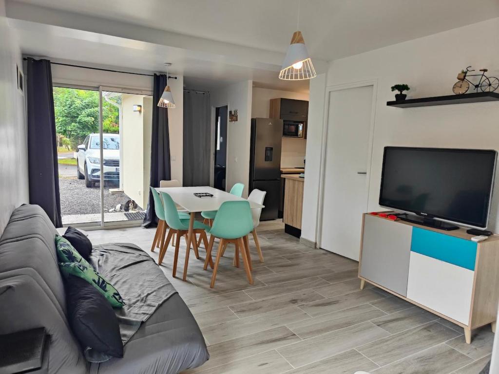 un salon avec un canapé, une télévision et une table dans l'établissement Maison climatisée proche Arcachon, à Gujan-Mestras