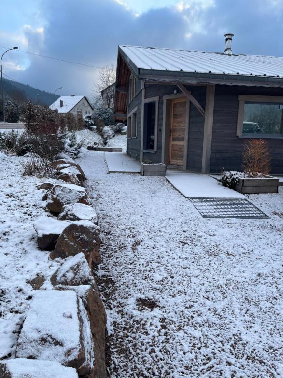 Una casa con nieve en el suelo delante de ella. en Les Loutrons, en Cornimont