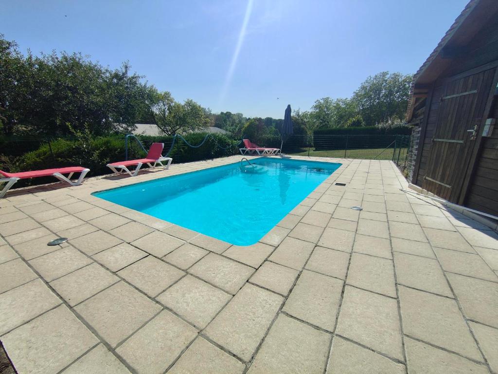 una piscina in un cortile con due sedie intorno di Les gîtes du Zoo,2 logements 10min du zoo piscine partagée juin-octobre & spa partagée avril-octobre ,calme & reposant a Châteauvieux