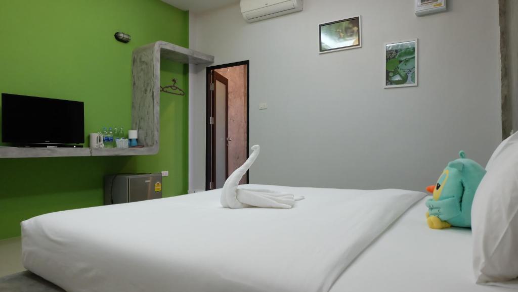 1 dormitorio con cama blanca y pared verde en Lullaby Boutique Resort, en Thap Sakae