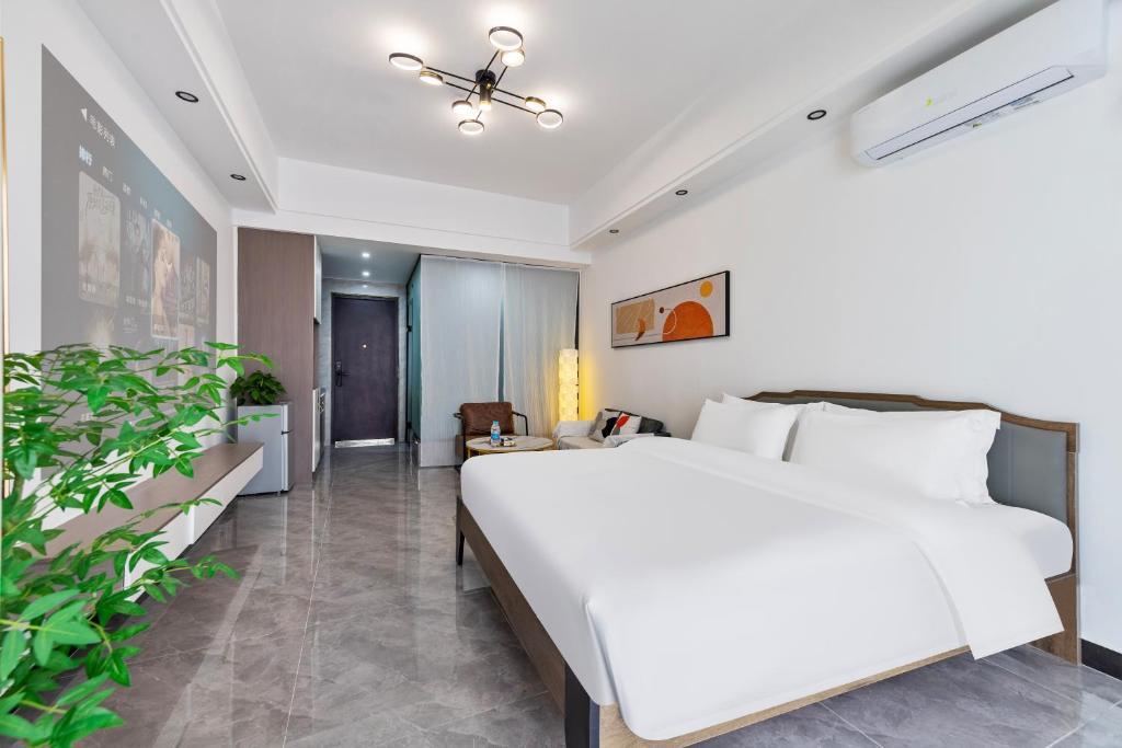 a bedroom with a large white bed and a plant at 张家界博亭安屿设计师民宿 in Zhangjiajie