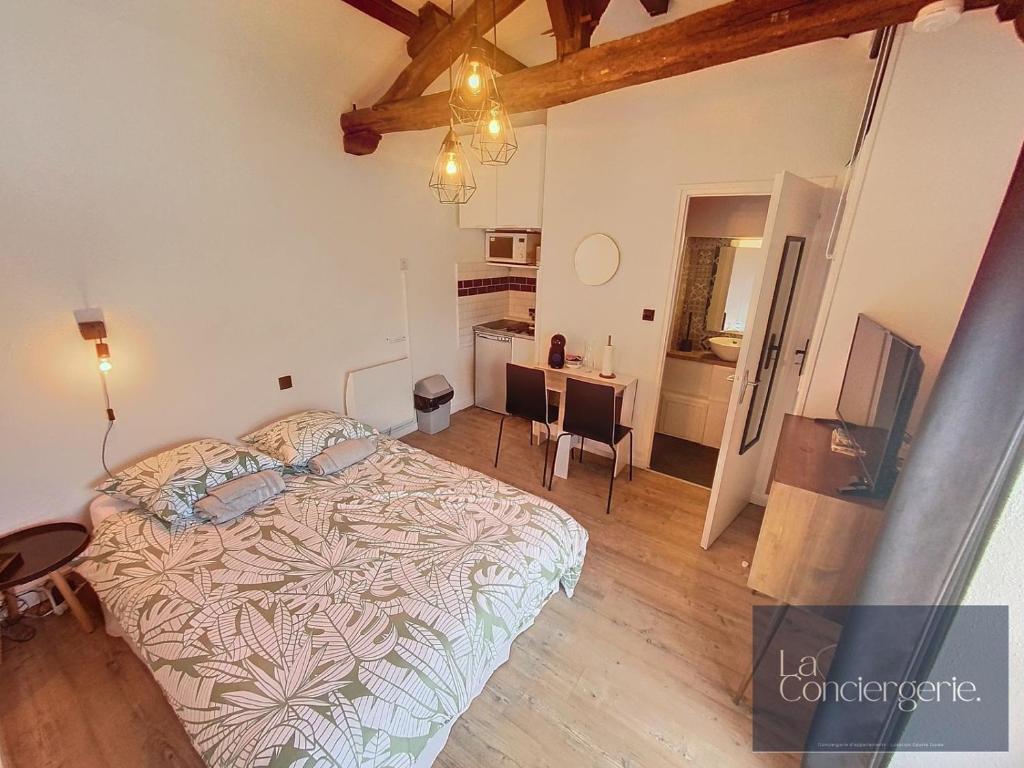 a bedroom with a large bed and a kitchen at Le Studio Augouard - Calme &Cosy in Poitiers