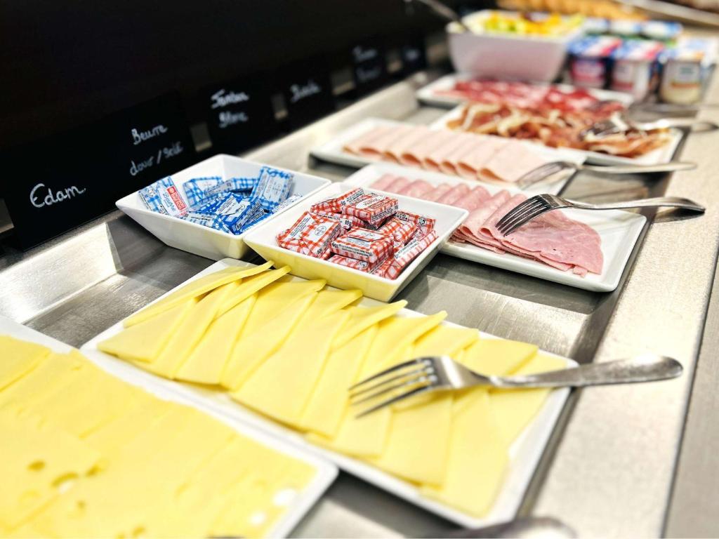 un buffet avec des assiettes de nourriture et d'ustensiles dans l'établissement ibis Styles Rouen Nord-Barentin, à Barentin