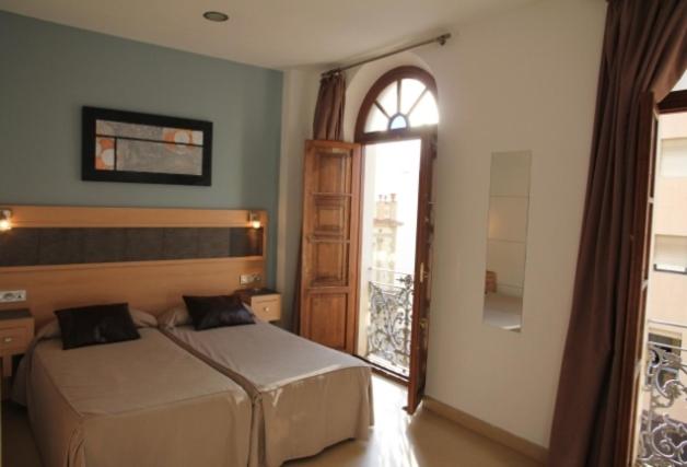 1 dormitorio con 2 camas y ventana en Hostal Plaza Ruiz, en Ceuta