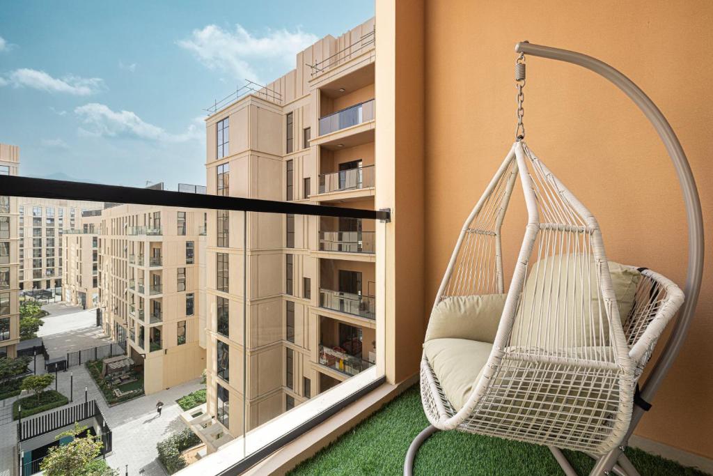 1BR Apartment With Balcony - 9 Mins to Sharjah Airport - Balcony Breeze في الشارقة: أرجوحة على شرفة مطلة على مدينة