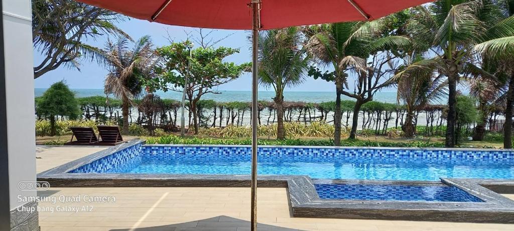 ein Pool mit Sonnenschirm und das Meer in der Unterkunft VILLA ARIA RESORT, THE SEA BY 10-50m,Biển và hồ bơi riêng in Vũng Tàu