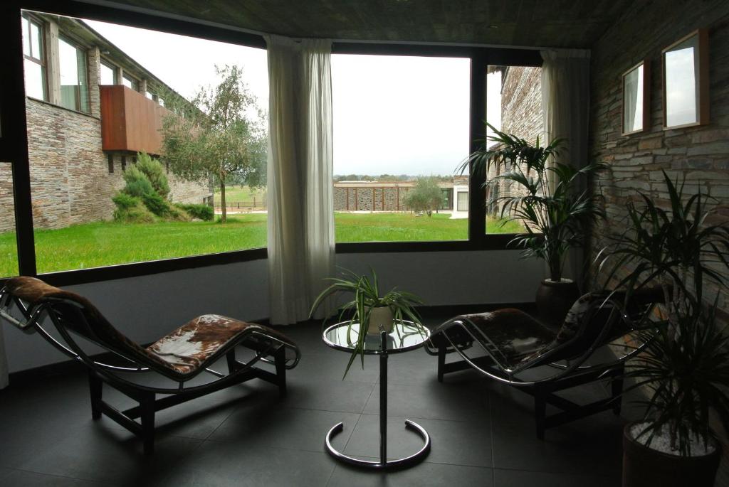 2 sillas y una mesa en una habitación con ventanas en Hotel Parque de Monfragüe, en Torrejón el Rubio