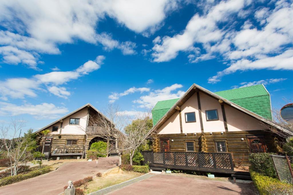 two wooden houses with green roofs on a road at Fiore Shima in Shima