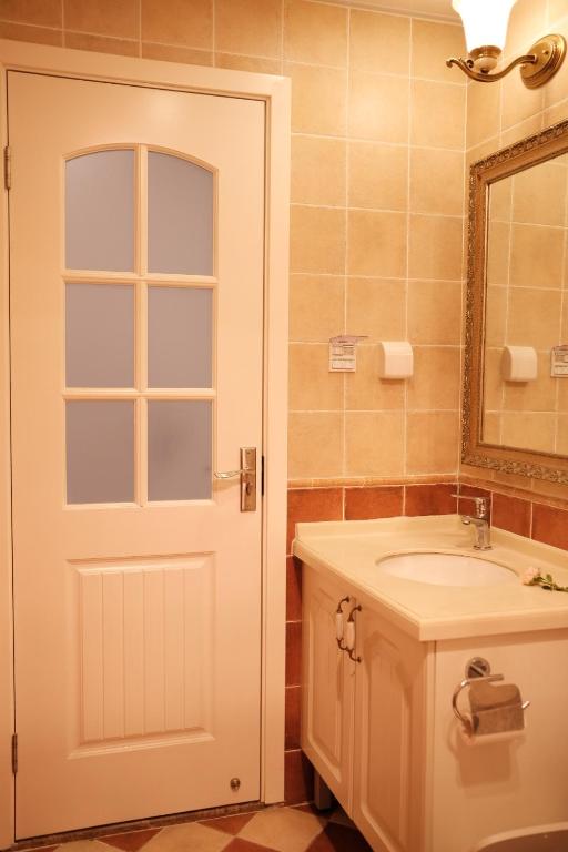 a bathroom with a sink and a mirror and a door at 福来小院民宿 in Jiezi Ancient Town