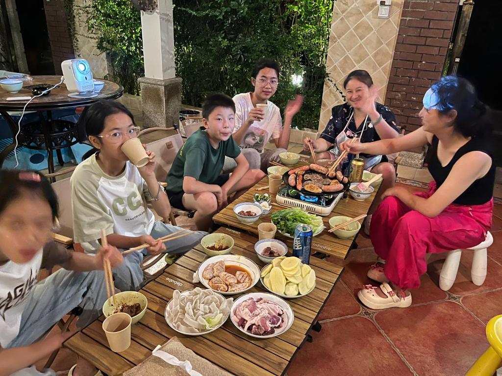 a group of people sitting around a table eating food at 福来小院民宿 in Jiezi Ancient Town