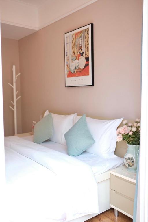 a bedroom with a white bed and a picture on the wall at 福来小院民宿 in Jiezi Ancient Town