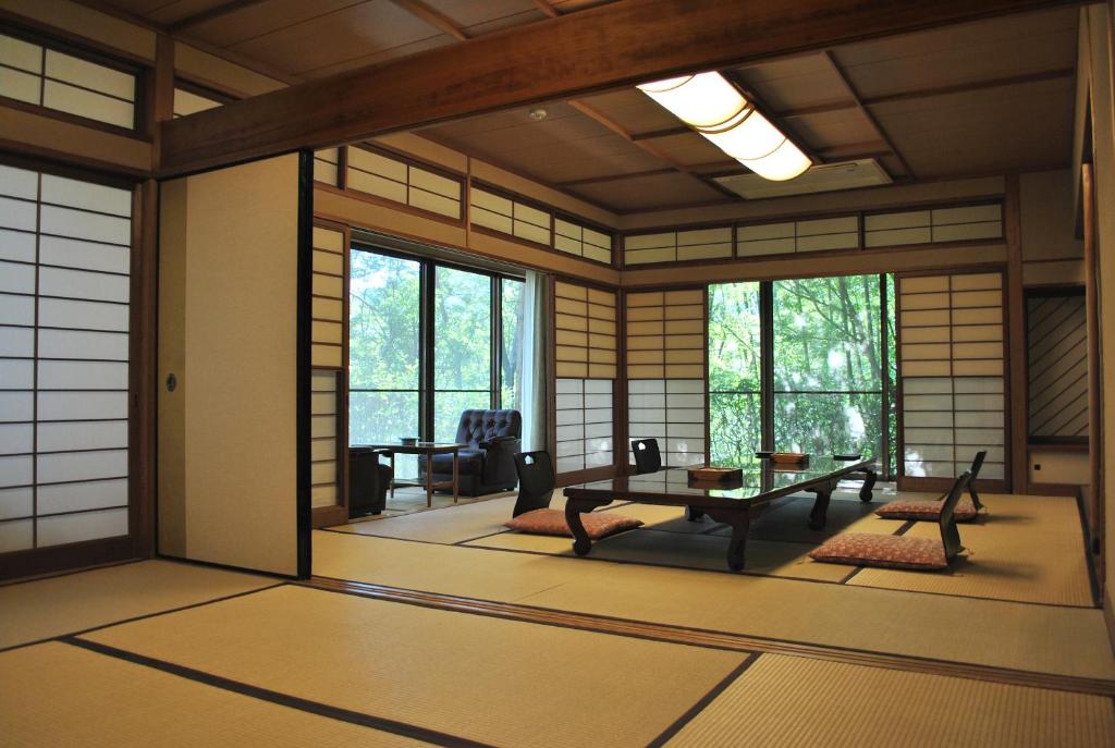 a japanese room with a table and chairs and windows at Negiya Ryofukaku in Kobe