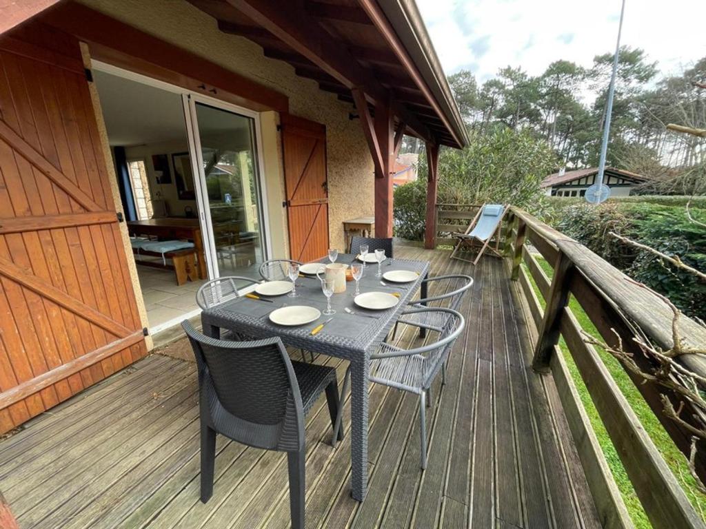 une table et des chaises noires sur une terrasse en bois dans l'établissement Maison Landaise au Calme - Proche Golf d'Hossegor, 3 Chambres, Jardin, Terrasse, Animaux Admis - FR-1-413-200, à Capbreton