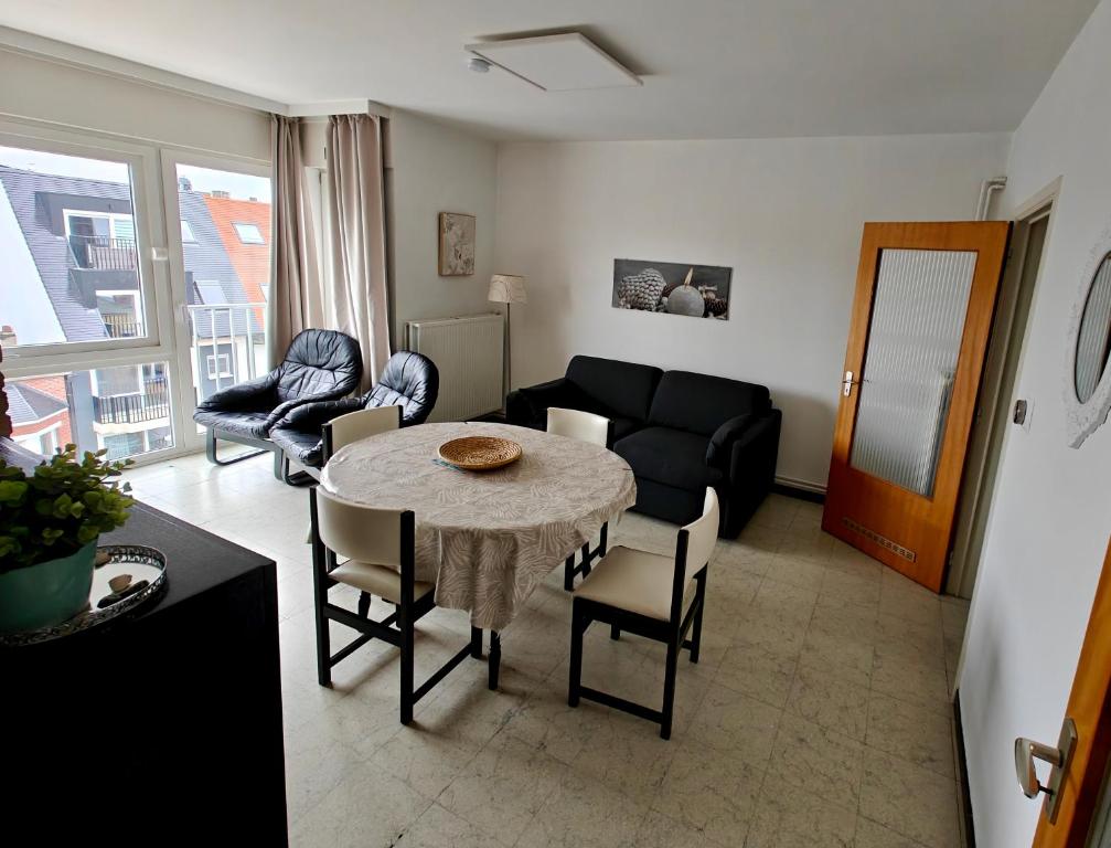 ein Wohnzimmer mit Tisch und Stühlen und einer Couch in der Unterkunft Le Zandkreek Plage & Centre - 2 Ch in Koksijde