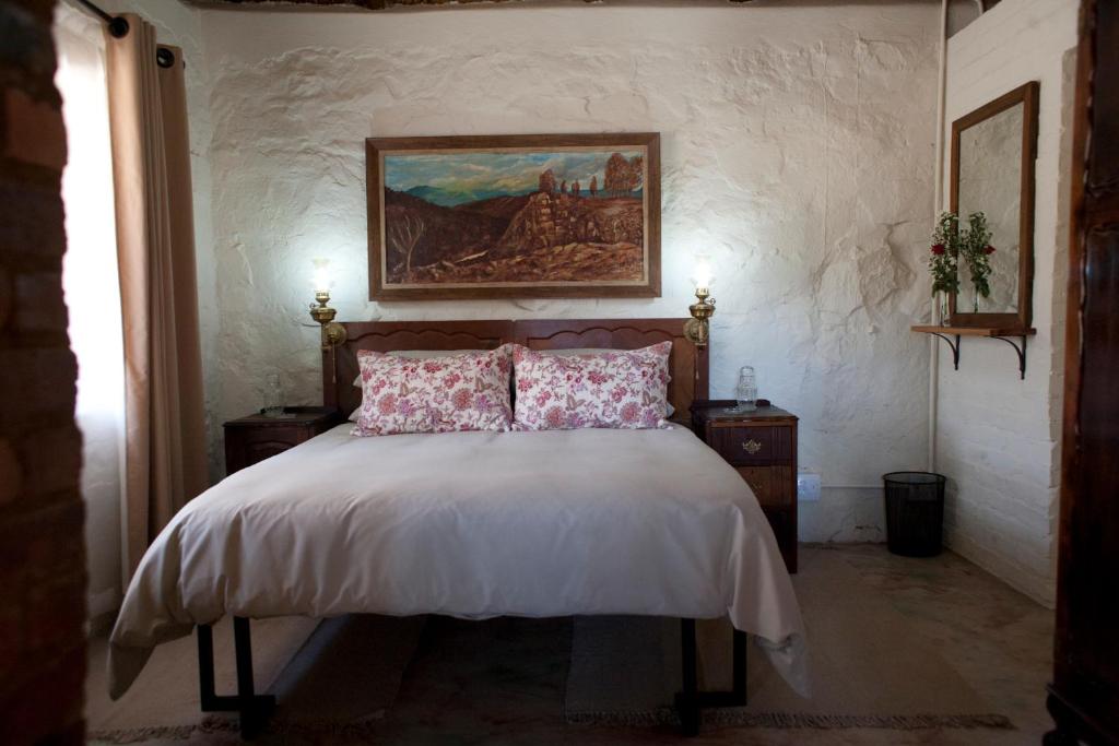 een slaapkamer met een bed met een schilderij aan de muur bij Stone Cottage in Tierpoort