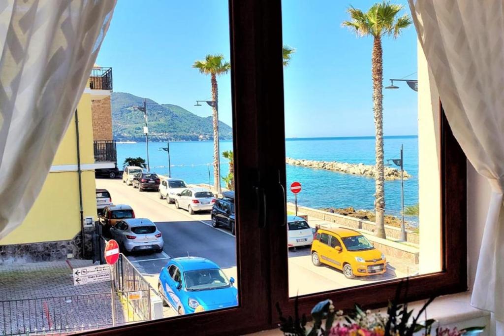 ein Fenster mit Blick auf eine Straße und Palmen in der Unterkunft Appartamento panoramico per 4 sul lungomare di Castellabate in Santa Maria di Castellabate