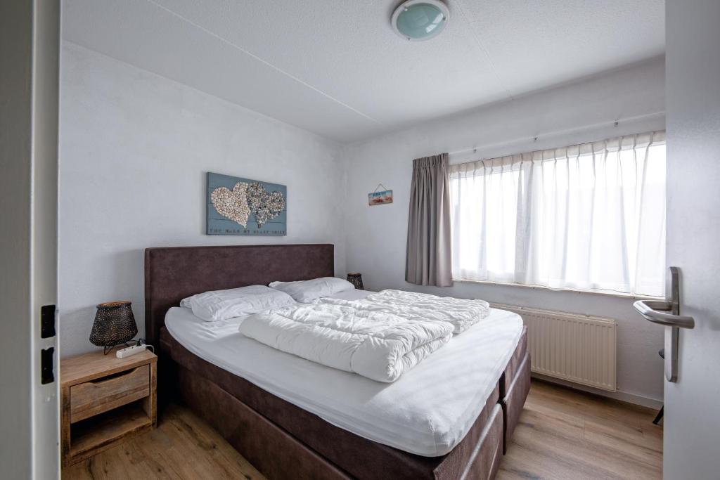 een slaapkamer met een groot bed en een raam bij Appartementencomplex Motel Texel in De Koog