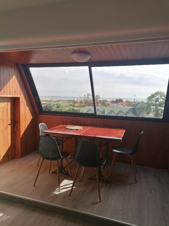 une table et des chaises dans une pièce avec une grande fenêtre dans l'établissement Vistamare sur Juno Beach - Vue Mer 4 pers, à Courseulles-sur-Mer