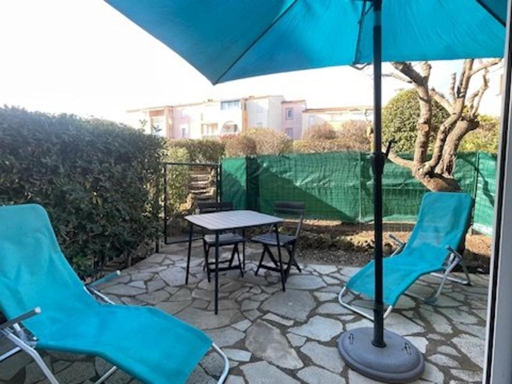 une table et des chaises avec un parasol sur une terrasse dans l'établissement Agréable T2 RDC avec parking et piscine au Cap d'Agde - FR-1-749-82, au Cap d'Agde