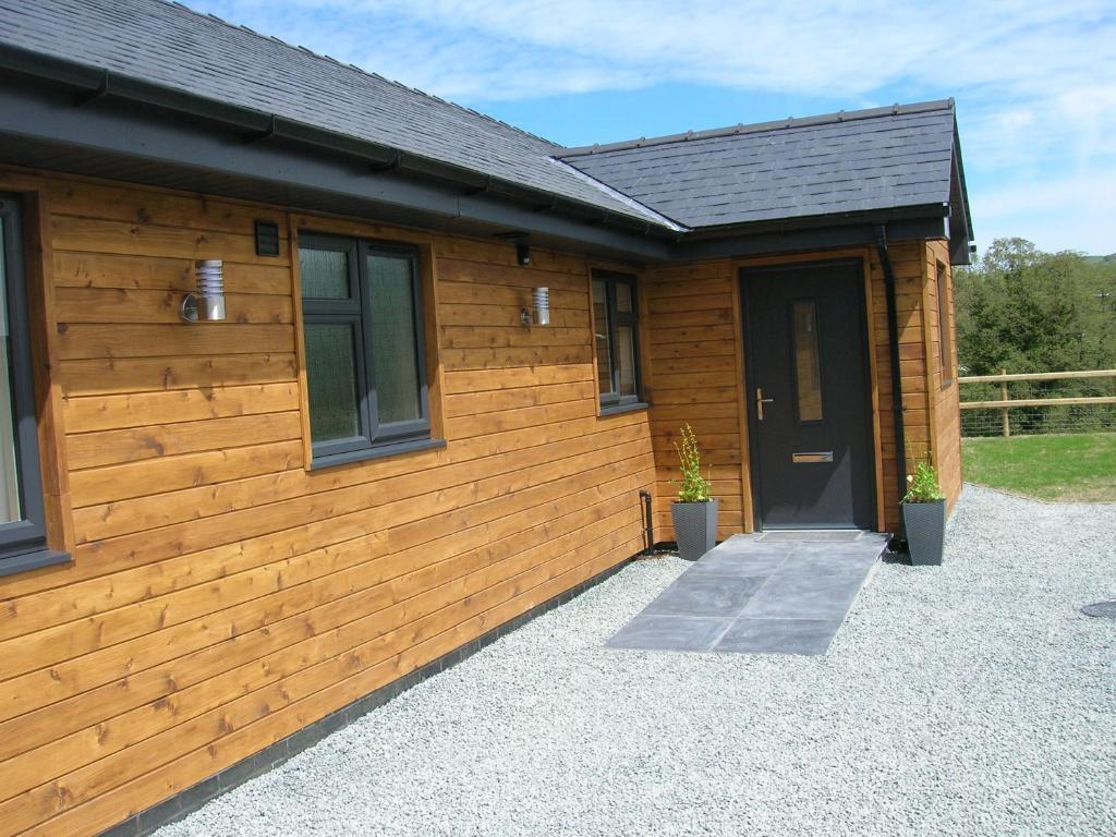 un edificio de madera con una puerta y dos macetas en Woodland Lodge Hot Tub Sleeps 6, en Hundred House