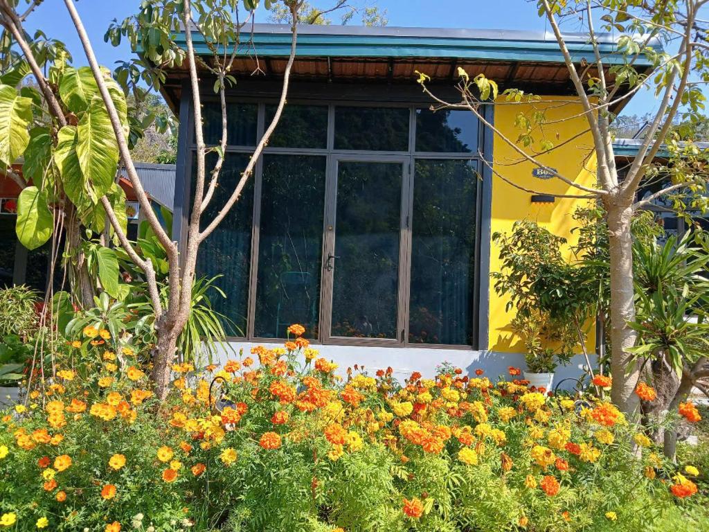a yellow house with a bunch of flowers in front of it at Catba Papillon Garden Bungalows & Resort in Cat Ba