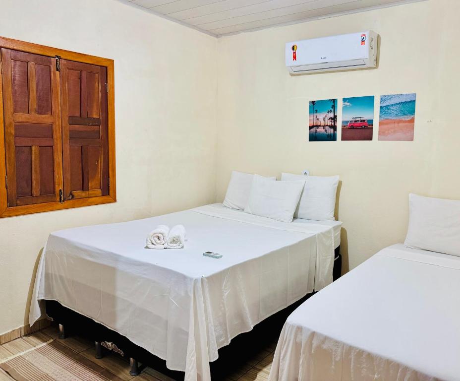 a room with two beds and a door at Hospedaria Hibisco Xandó - Caraíva in Caraíva