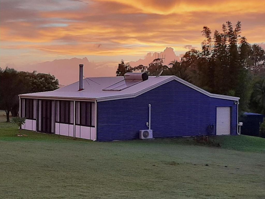a blue building with a roof on a field at Sanctuary Hills Cottage in Takura