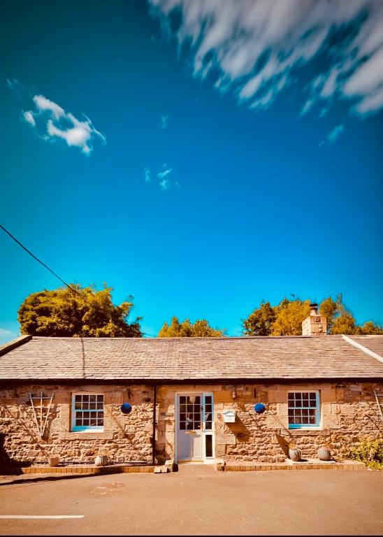 an old stone building with a blue sky at HomeDecor Cottages - Old Stable House in Alnwick