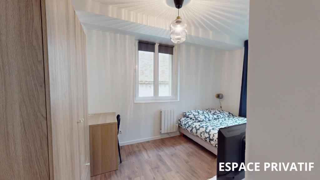 une petite chambre avec un lit et une fenêtre dans l'établissement Coty - chambre 1, au Havre