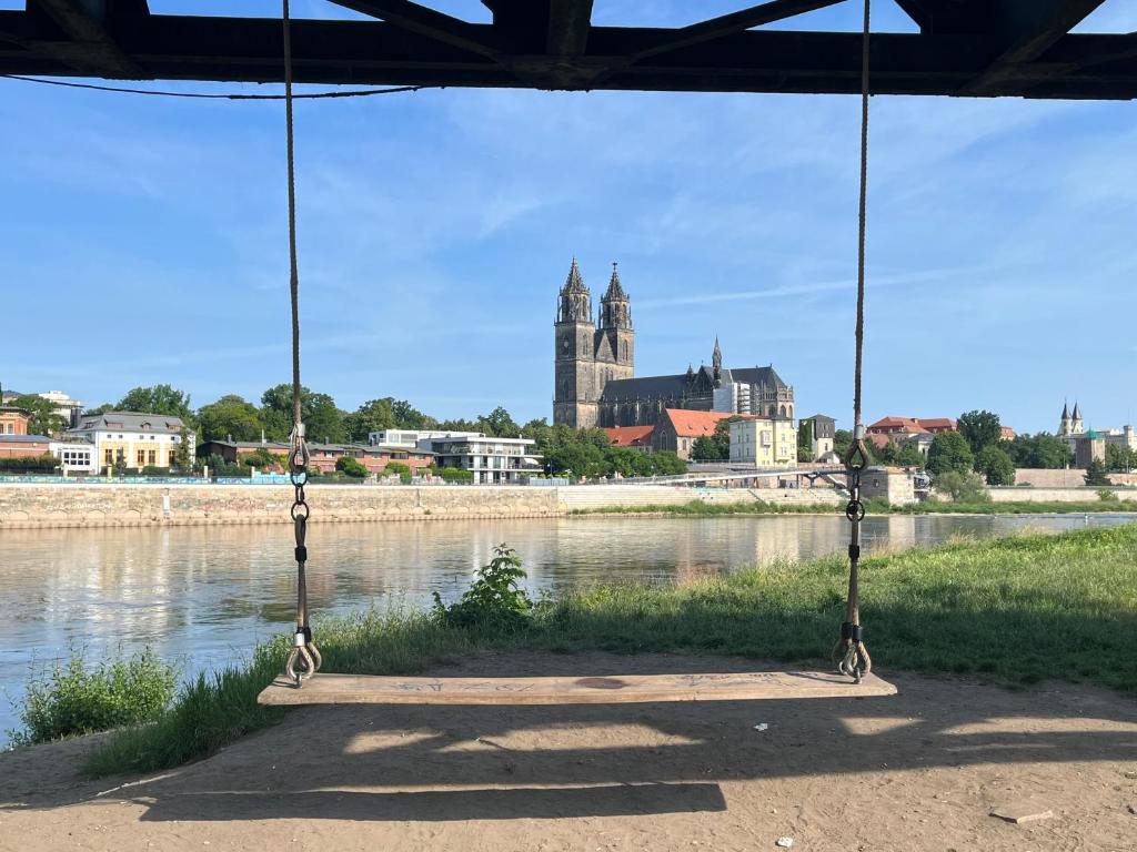 a swing in front of a river with a church at Elbidyll in Magdeburg