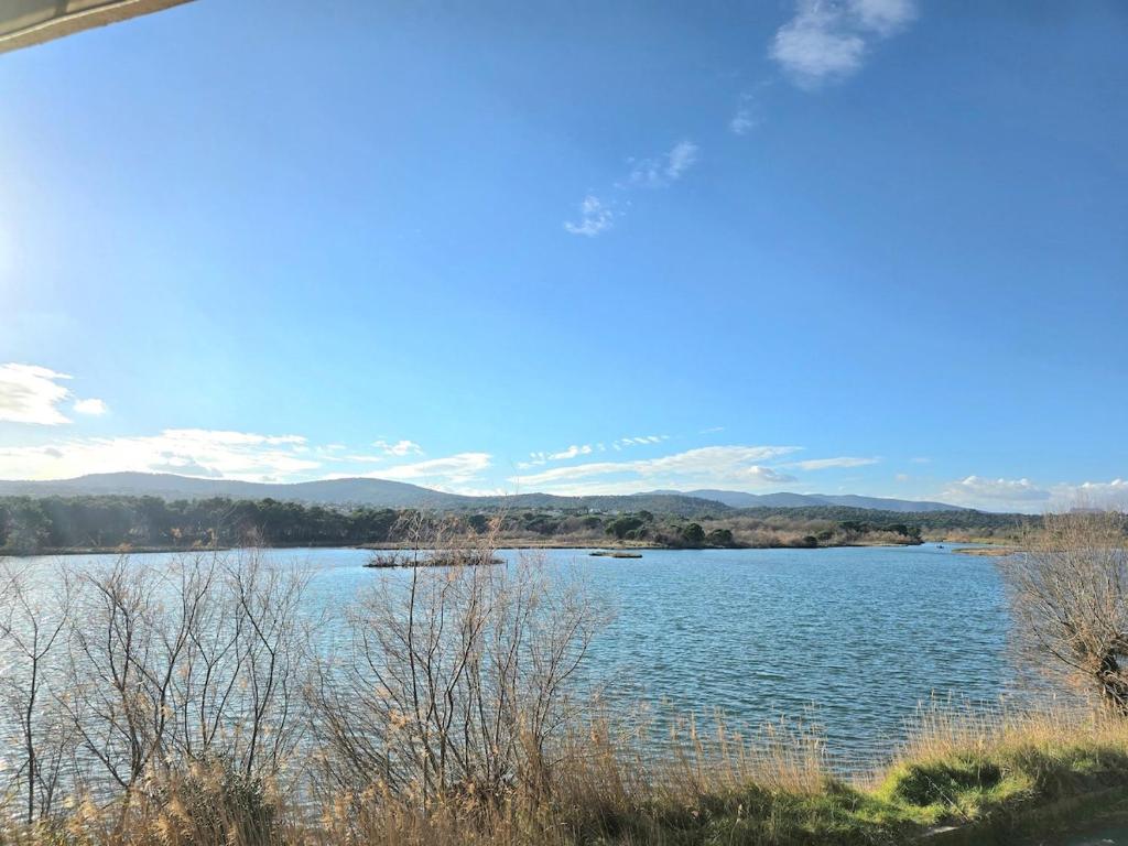 une vue d'un lac avec des montagnes en arrière-plan dans l'établissement Venise1, 4 pers, front de mer, vue étang, clim, à Fréjus