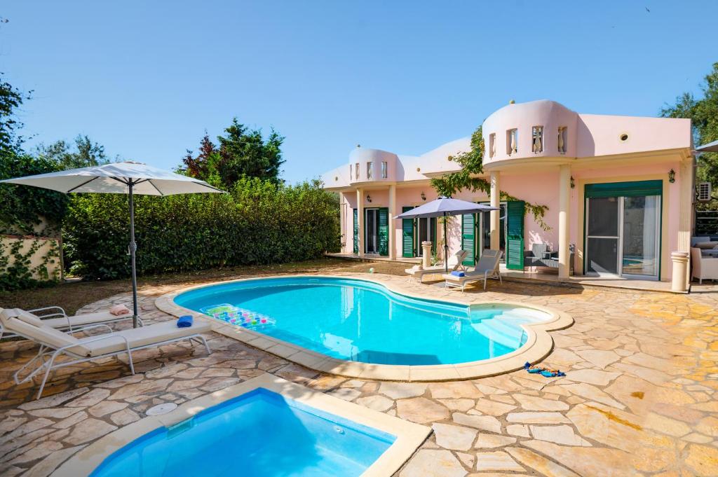 a house with a swimming pool and an umbrella at Villa Zaira in Halikounas