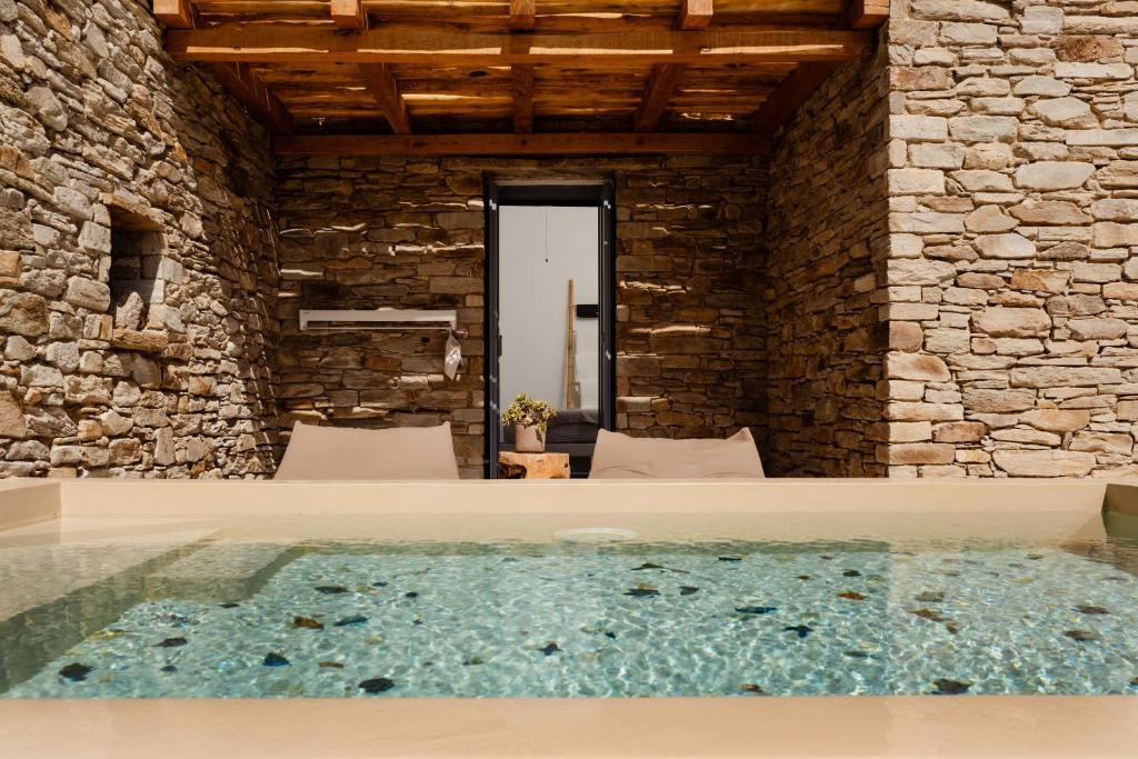 a bath tub in a room with a stone wall at Gianemma Luxury Apartments in Mylopotas