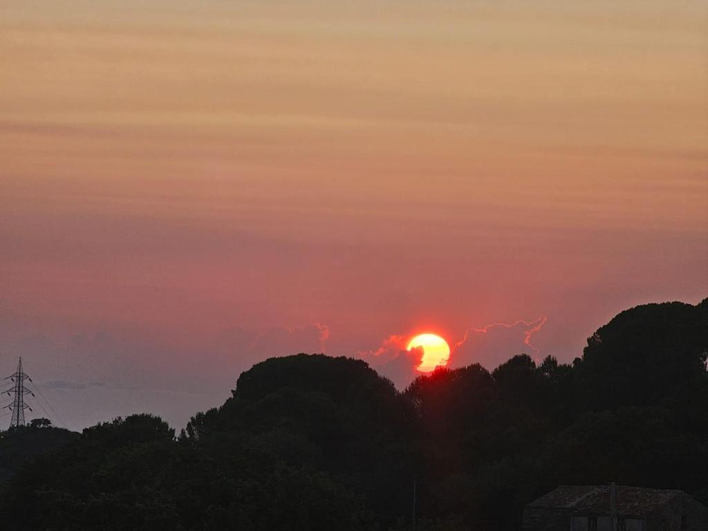 un tramonto con il sole che tramonta sugli alberi di Borgo Vignale a Santuario di Gibilmanna