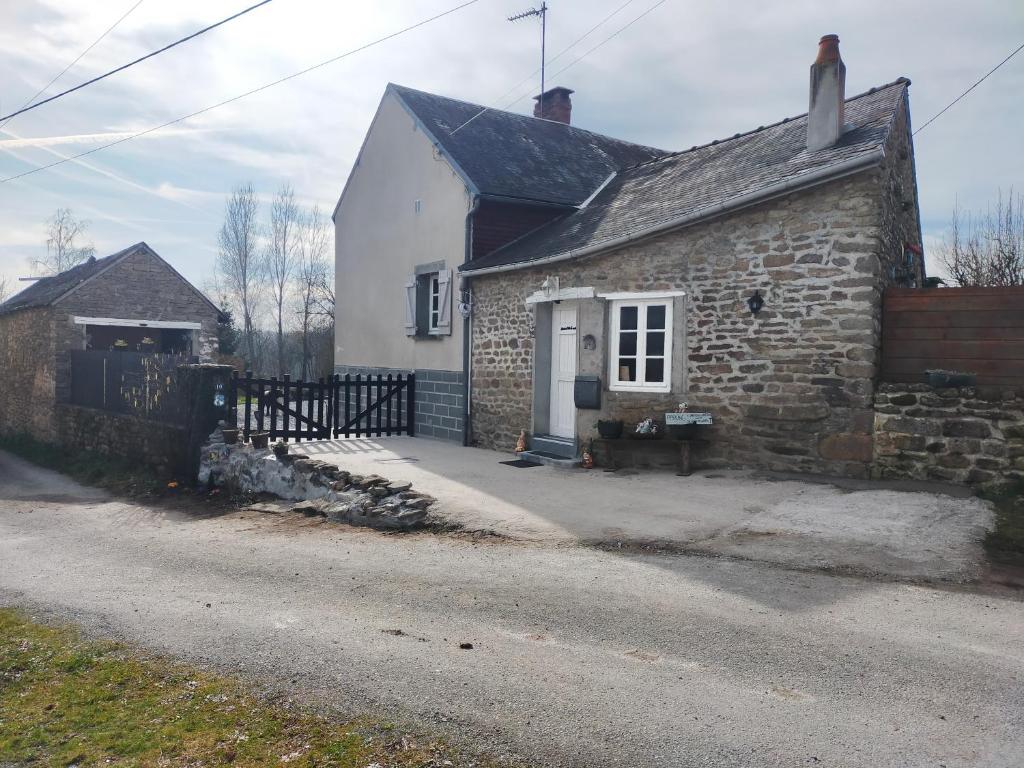 an old stone house with a white door and a fence at Chambre d'hôtes Se Sentir Libre Noisette in Crozant