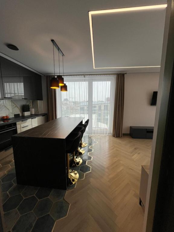 Una sala de estar con una mesa y una cocina. en WAVE Apartaments Vilnius, en Vilna