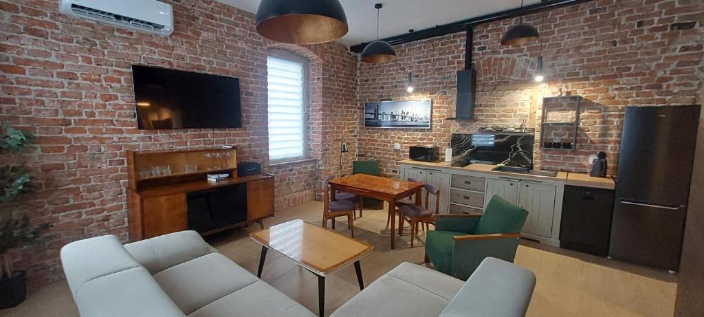 een keuken en een woonkamer met een bakstenen muur bij Apartament Przygórze 212 in Przygórze