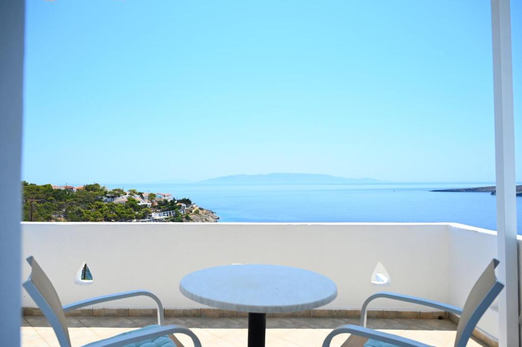 a table and chairs on a balcony with a view of the ocean at Oneiro Rooms Kythnos in Kanala