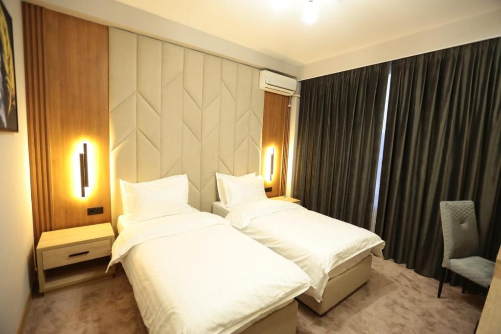 a hotel room with two beds and a chair at Sem Brand Hotel in Türkistan