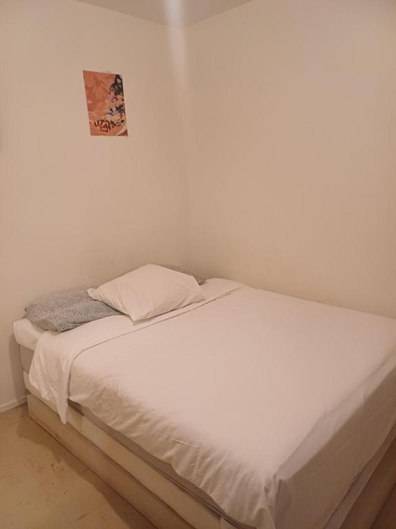 - un lit blanc dans une chambre blanche avec une photo sur le mur dans l'établissement Saphire tilleul, à Nantes