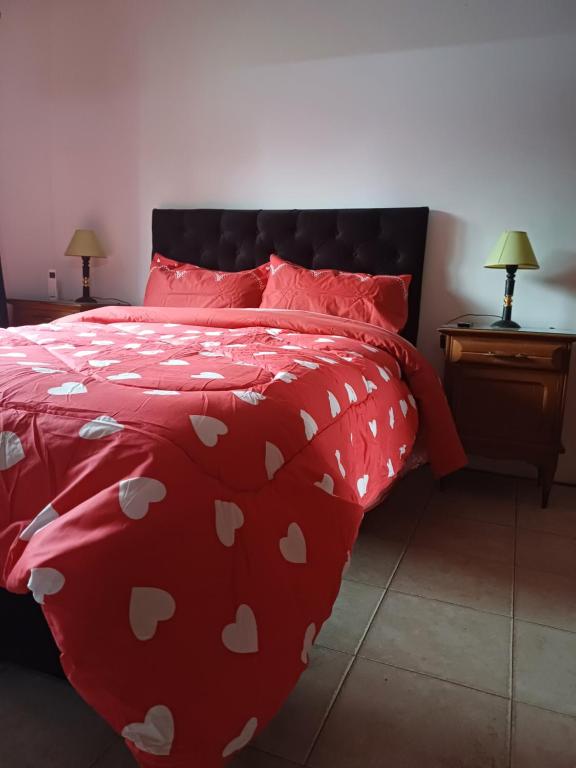 una cama roja con un edredón rojo con corazones blancos en La Quintita, en Villa Elisa